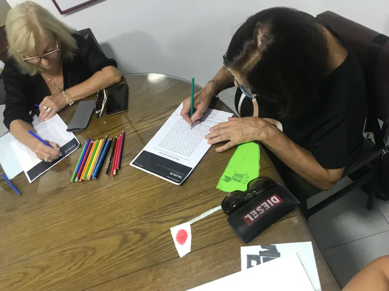 Dos alumnas trabajando con consignas impresas y lápices de colores
