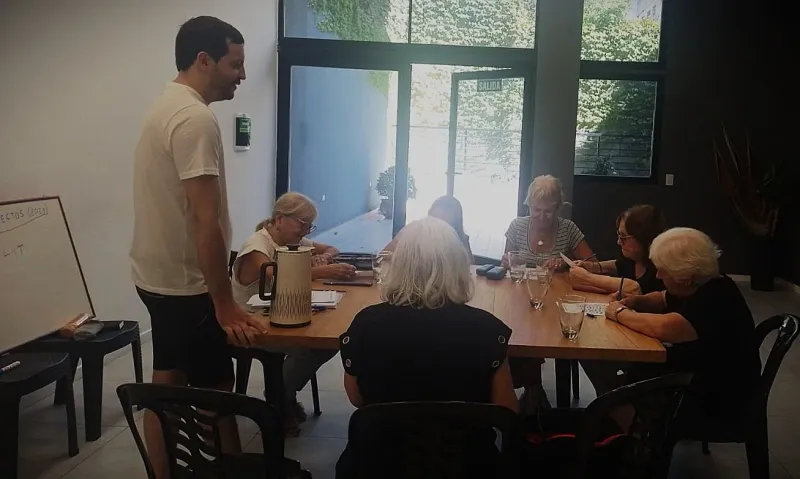 Ramiro coordinando de pie una actividad grupal mientras los alumnos trabajan en la mesa