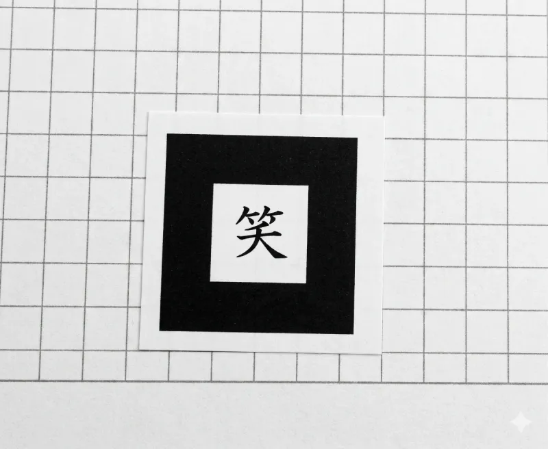 Marcador imprimible de Realidad Aumentada con el Kanji 笑 sobre papel cuadriculado, usado para disparar la app
