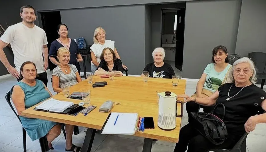 Alumnos y alumnas del taller junto a los coordinadores, reunidos alrededor de una mesa de trabajo